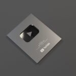 YouTube Silver Button Award for achieving 100K subscribers displayed on a table